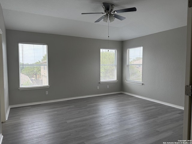 unfurnished room featuring a ceiling fan, dark wood-style floors, and plenty of natural light