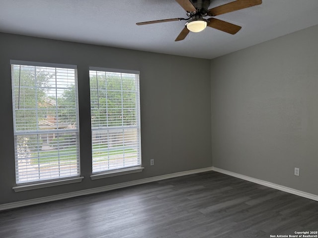empty room featuring baseboards, plenty of natural light, and dark wood-style flooring