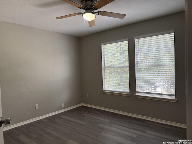 spare room featuring baseboards, ceiling fan, and dark wood-style floors