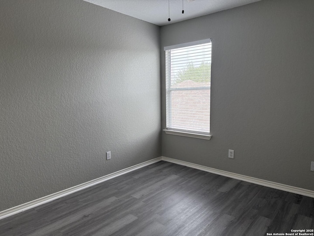empty room featuring baseboards and dark wood-style flooring