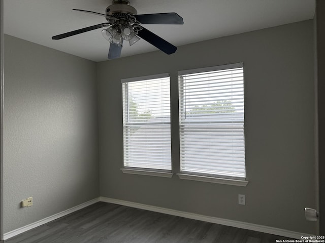 empty room featuring baseboards, a ceiling fan, and dark wood-style flooring