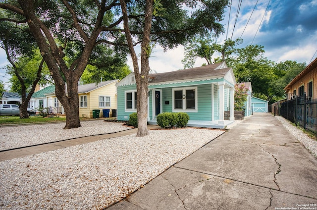 view of front of property featuring an outdoor structure, fence, metal roof, a porch, and driveway