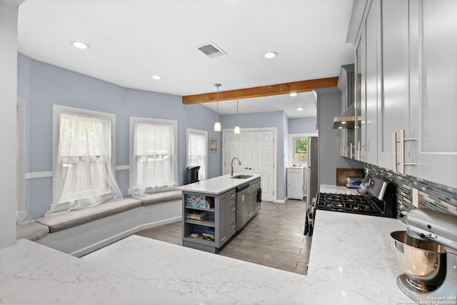 kitchen with beam ceiling, gray cabinets, light wood-style flooring, stainless steel appliances, and visible vents