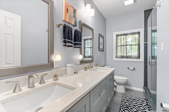 bathroom with double vanity, toilet, a sink, and a stall shower