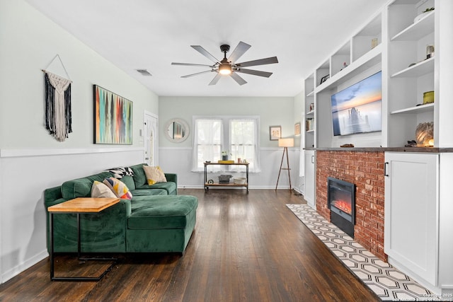 living area with visible vents, a ceiling fan, dark wood finished floors, and a brick fireplace
