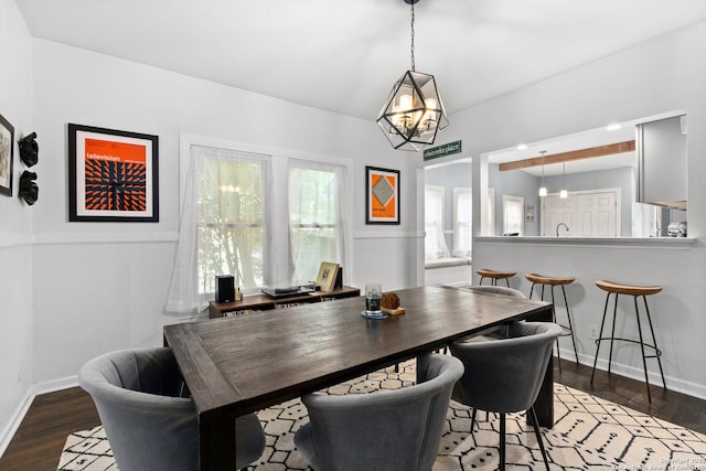 dining space with baseboards, wood finished floors, and a chandelier
