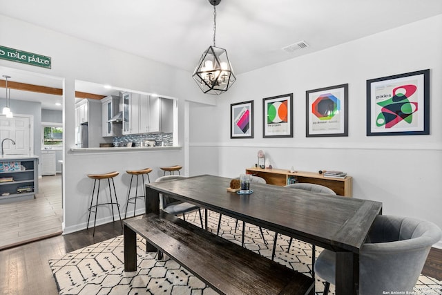 dining area with a chandelier, visible vents, and hardwood / wood-style floors