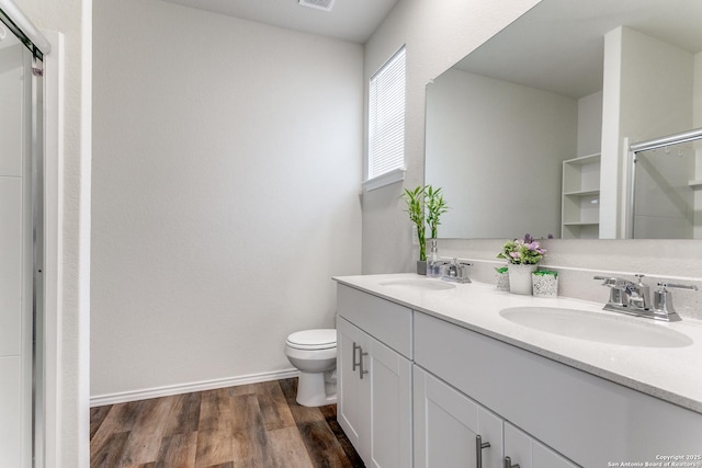 bathroom featuring wood finished floors, a sink, a stall shower, and toilet