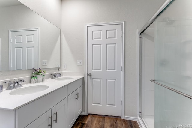bathroom with a sink, double vanity, a stall shower, and wood finished floors