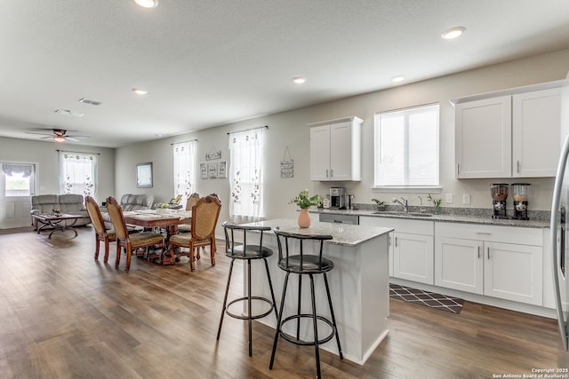 kitchen with a ceiling fan, a kitchen island, a kitchen bar, a sink, and recessed lighting