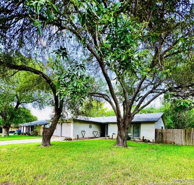 ranch-style home with an attached garage, fence, driveway, and a front yard