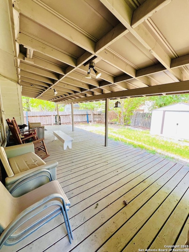 wooden terrace with a fenced backyard, a shed, and an outbuilding