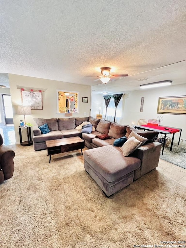 carpeted living area with a textured ceiling and ceiling fan