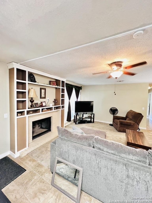 living area with a textured ceiling, ceiling fan, baseboards, and a fireplace