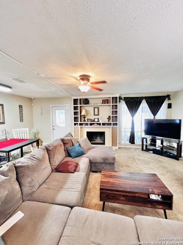 carpeted living room with a textured ceiling, ceiling fan, visible vents, and a fireplace