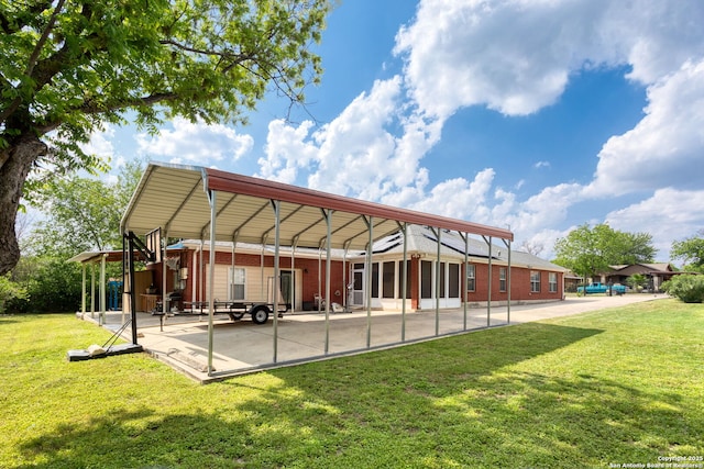 back of house with a lawn, a carport, and brick siding