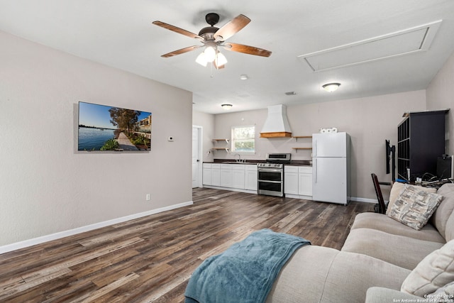 living area with a ceiling fan, baseboards, attic access, and dark wood-type flooring