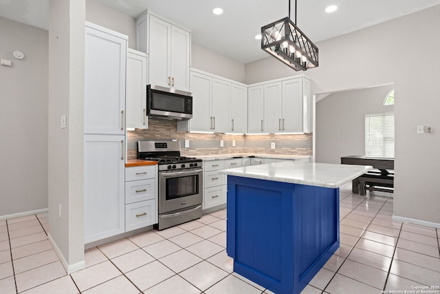 kitchen with decorative backsplash, a kitchen island, appliances with stainless steel finishes, baseboards, and white cabinets