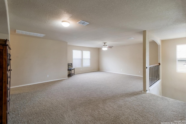 carpeted spare room featuring visible vents, a textured ceiling, ceiling fan, and baseboards