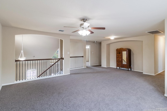 empty room with arched walkways, ceiling fan, carpet flooring, and visible vents