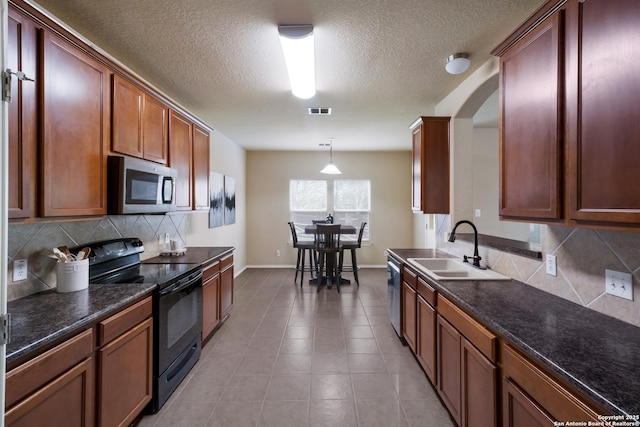 kitchen with decorative backsplash, baseboards, a textured ceiling, a sink, and stainless steel appliances