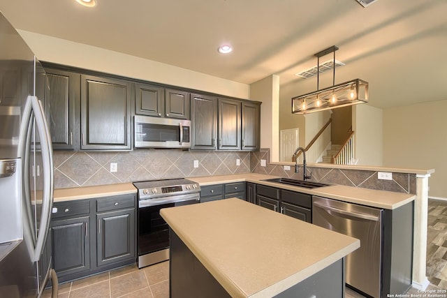 kitchen featuring a sink, stainless steel appliances, a peninsula, decorative backsplash, and visible vents