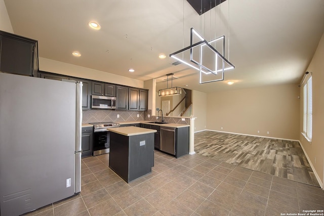 kitchen featuring a peninsula, open floor plan, light countertops, a sink, and appliances with stainless steel finishes
