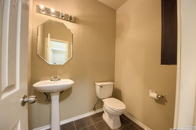bathroom featuring tile patterned flooring, baseboards, and toilet