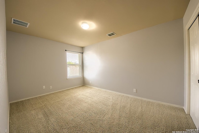 spare room featuring carpet floors, baseboards, and visible vents