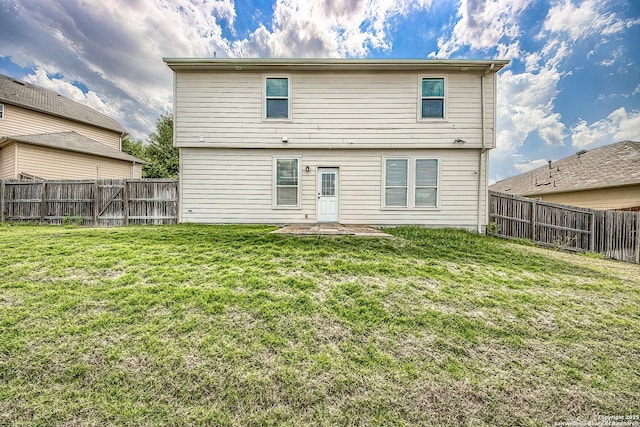 rear view of property featuring a fenced backyard and a lawn