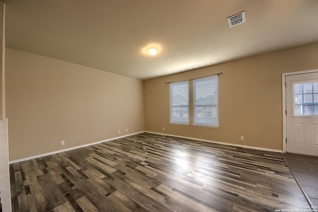 unfurnished room with baseboards, dark wood-style floors, and visible vents