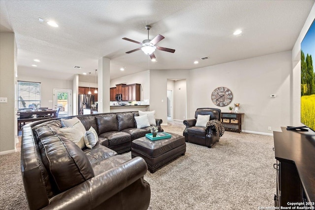carpeted living area featuring a ceiling fan, baseboards, and a textured ceiling