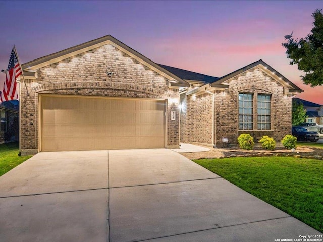 view of front of home with an attached garage, a front yard, driveway, and brick siding