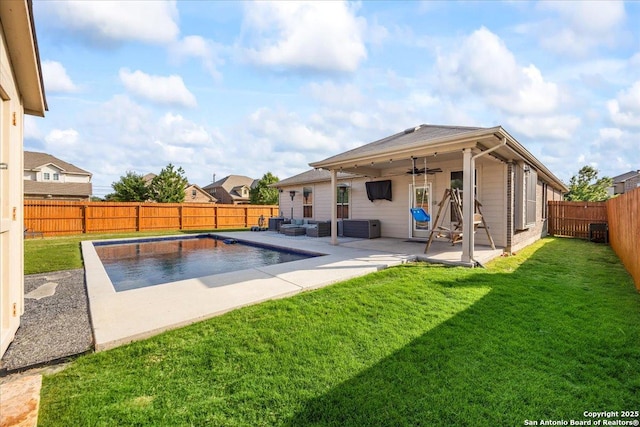 view of pool with a lawn, a ceiling fan, a patio area, and a fenced backyard