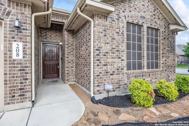 view of exterior entry featuring brick siding