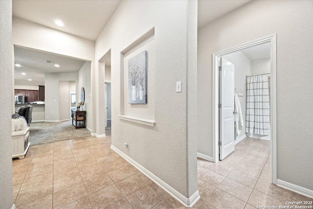corridor featuring recessed lighting, baseboards, and light tile patterned floors