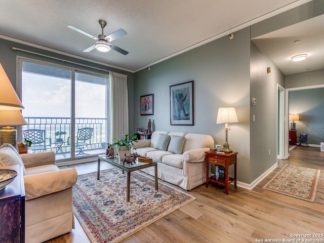 living room with baseboards, ornamental molding, ceiling fan, and wood finished floors