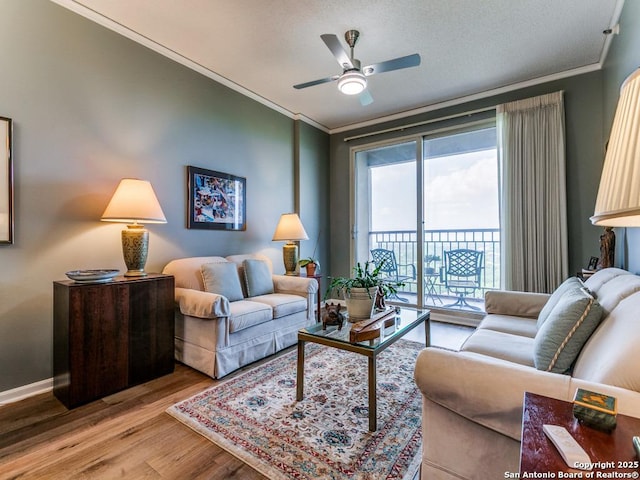 living area featuring baseboards, a ceiling fan, light wood-style flooring, and ornamental molding