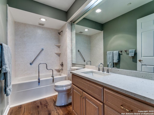 bathroom with vanity, toilet, tub / shower combination, wood finished floors, and visible vents