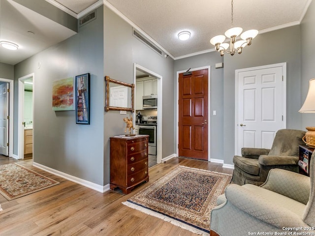 entryway with crown molding, a chandelier, wood finished floors, and visible vents