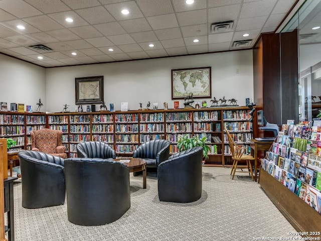 sitting room with wall of books, carpet floors, and visible vents