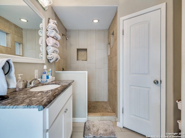 bathroom featuring a tile shower, tile patterned flooring, vanity, toilet, and recessed lighting