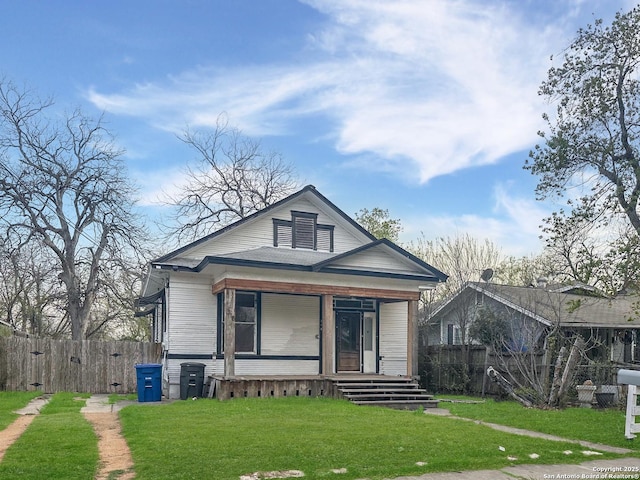 bungalow-style home with a porch, a front lawn, and fence