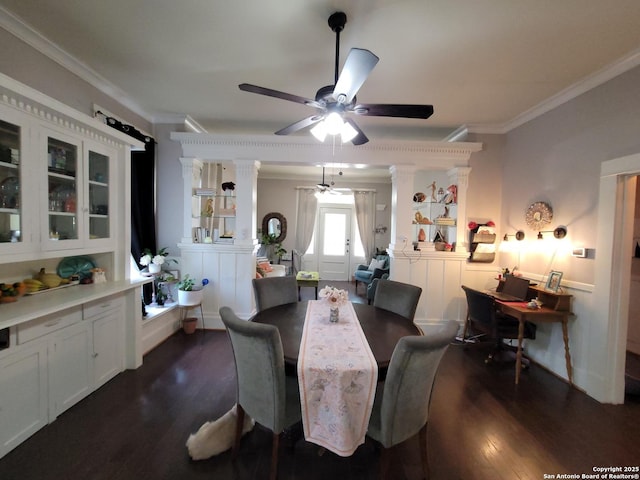 dining room with crown molding, a ceiling fan, decorative columns, and dark wood-style floors
