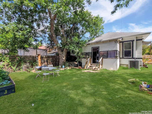 rear view of house featuring fence, central air condition unit, and a yard