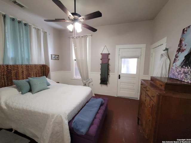 bedroom with a ceiling fan, visible vents, and wainscoting