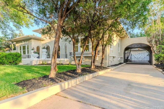 view of front facade with a gate, stucco siding, and a front lawn