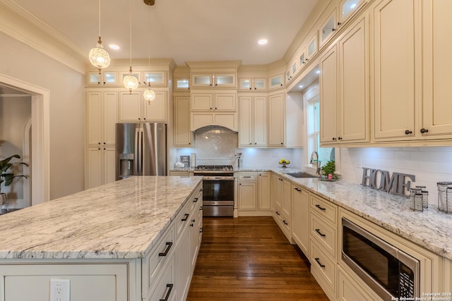 kitchen featuring stainless steel appliances, a sink, a center island, light stone counters, and recessed lighting