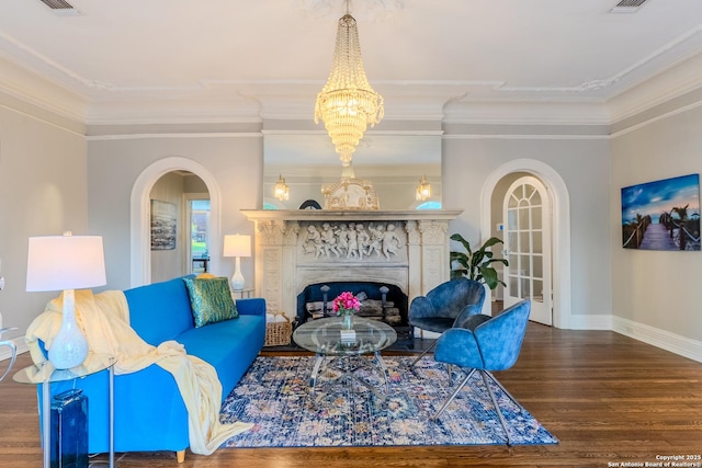 living area with wood finished floors, baseboards, ornamental molding, a premium fireplace, and arched walkways