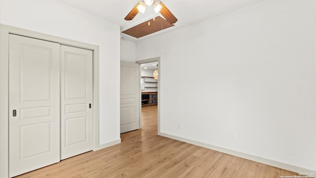unfurnished bedroom featuring light wood-style floors, attic access, baseboards, and a closet